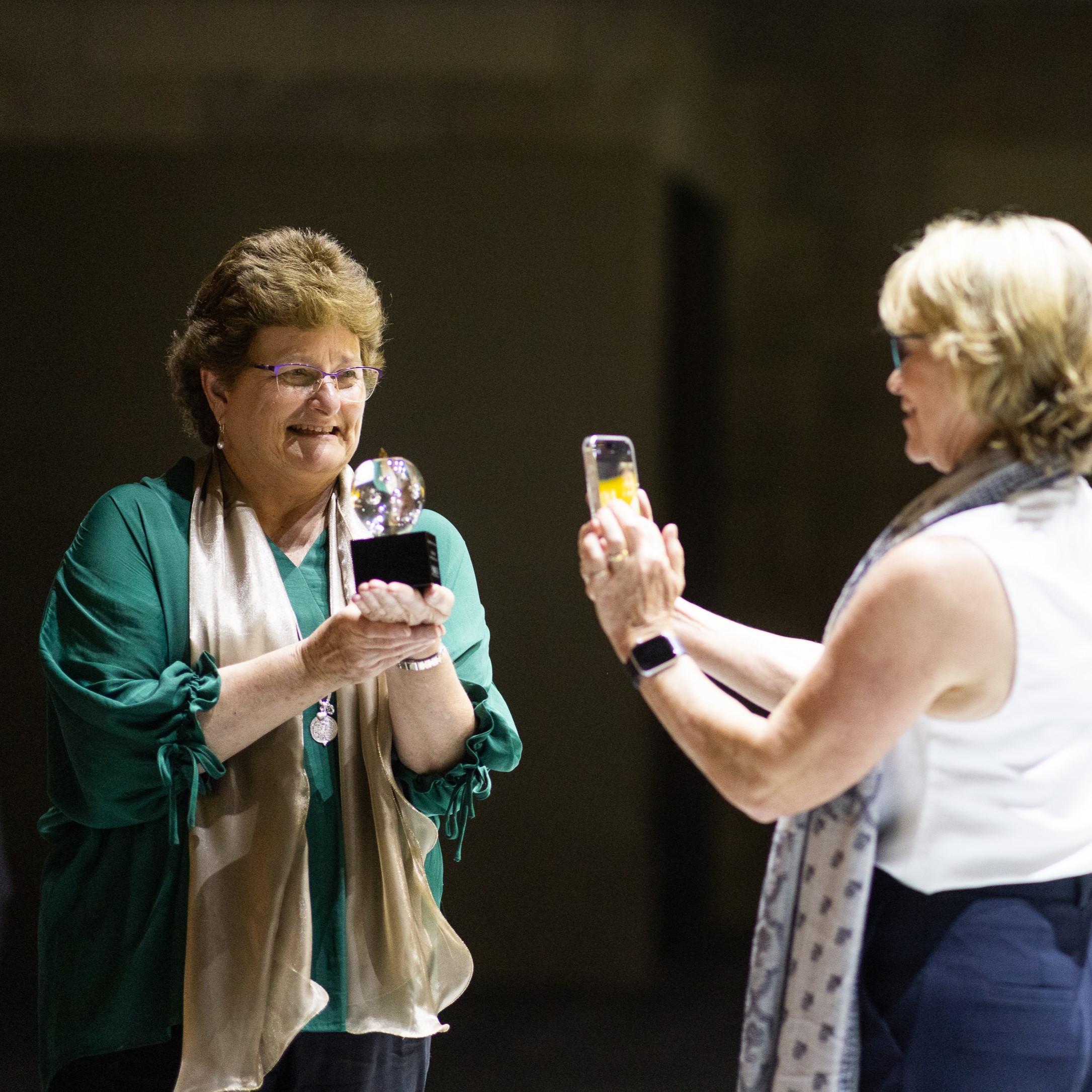 Mrs Peacey receiving a National Excellence in Teaching Award on stage while a colleague photographs the moment