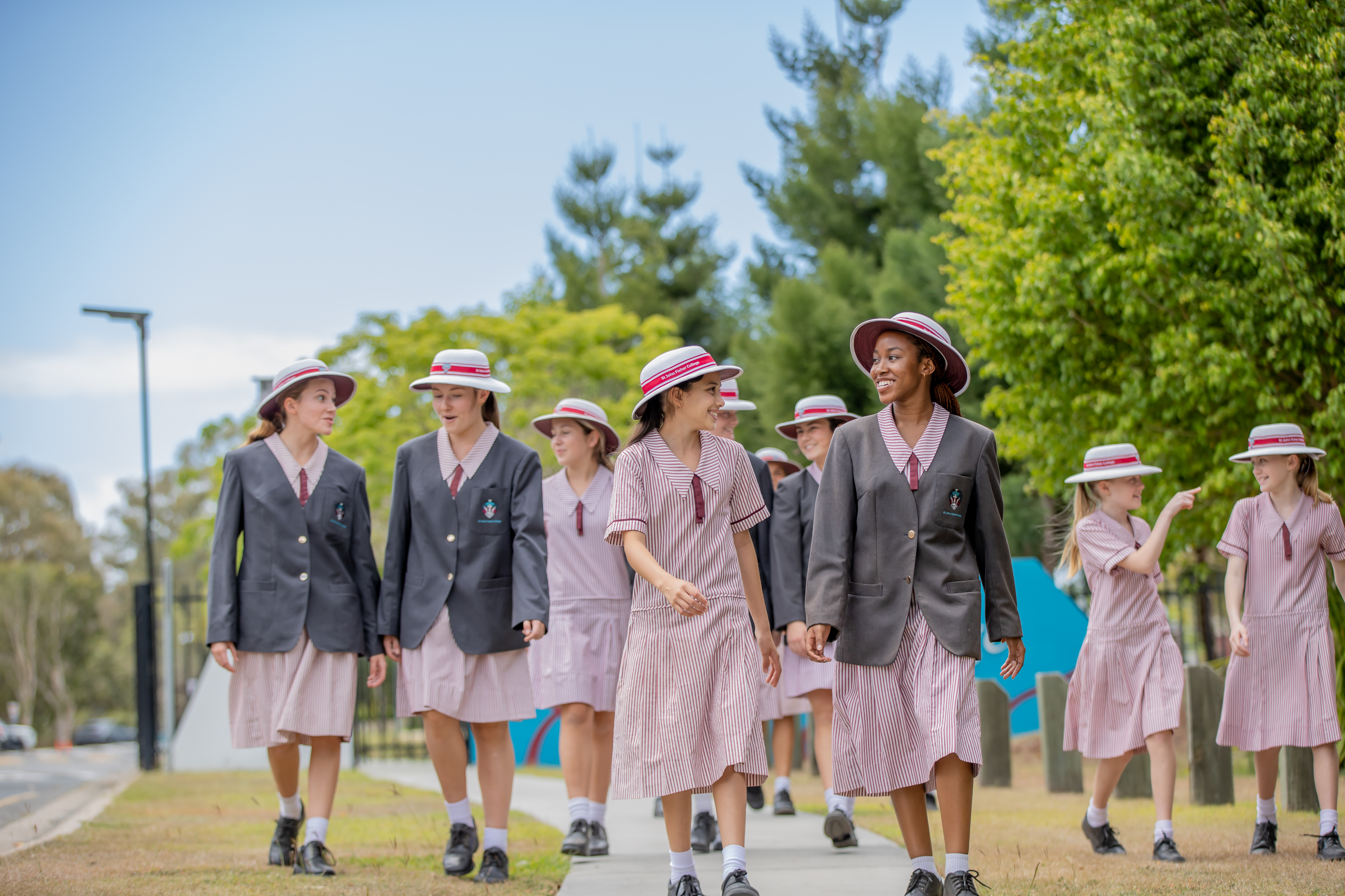 Students in school uniforms walking together along a path and talking outdoors